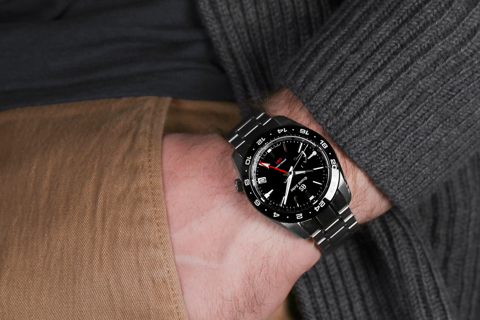 Grand Seiko SBGE253 black dial watch with red accents on the wrist.