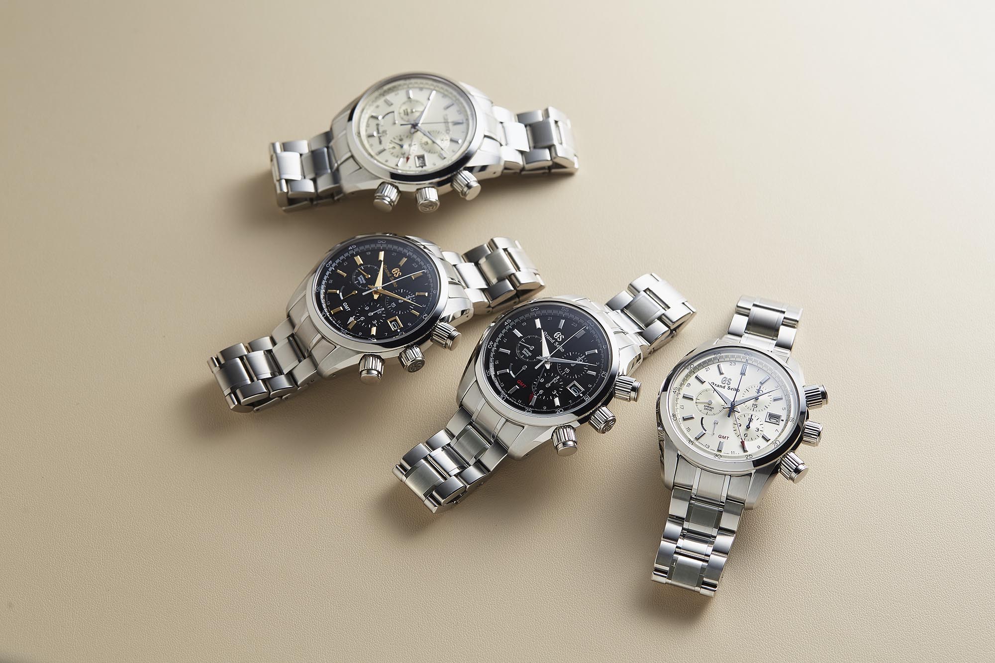 Four Grand Seiko chronographs on beige surface